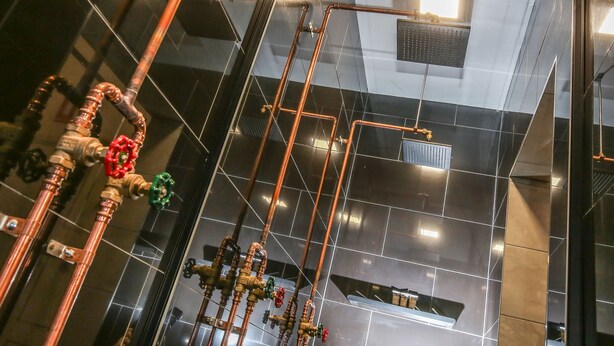 A modern bathroom with copper pipes and multiple faucets. - Indulge Apartments -The Urban Collection (Mildura)