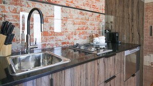 A modern kitchen with a black countertop, stainless steel sink, and wooden cabinets. - Indulge Apartments -The Urban Collection (Mildura)