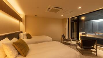 A hotel room with two beds, a seating area with chairs, and a large window offering a view.