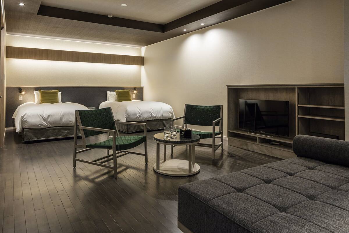Ein modernes Hotelzimmer mit zwei Betten, einer Couch, einem Fernseher und einem Kamin.