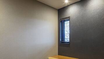 A room with two chairs, a bench, a small window, and a dark wall.