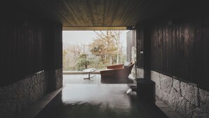 A modern interior with a wooden ceiling, stone walls, and a view of trees outside.