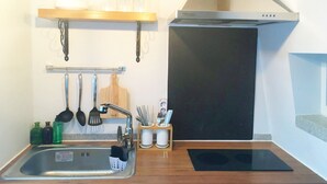 Eine Küche mit Edelstahl-Spüle, Holz Arbeitsplatte, hängenden Küchenutensilien und einer Dunstabzugshaube.