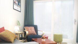 Ein modernes Wohnzimmer mit einer Couch, einem Sessel und einem kleinen Tisch mit Lampe und Dekoration.