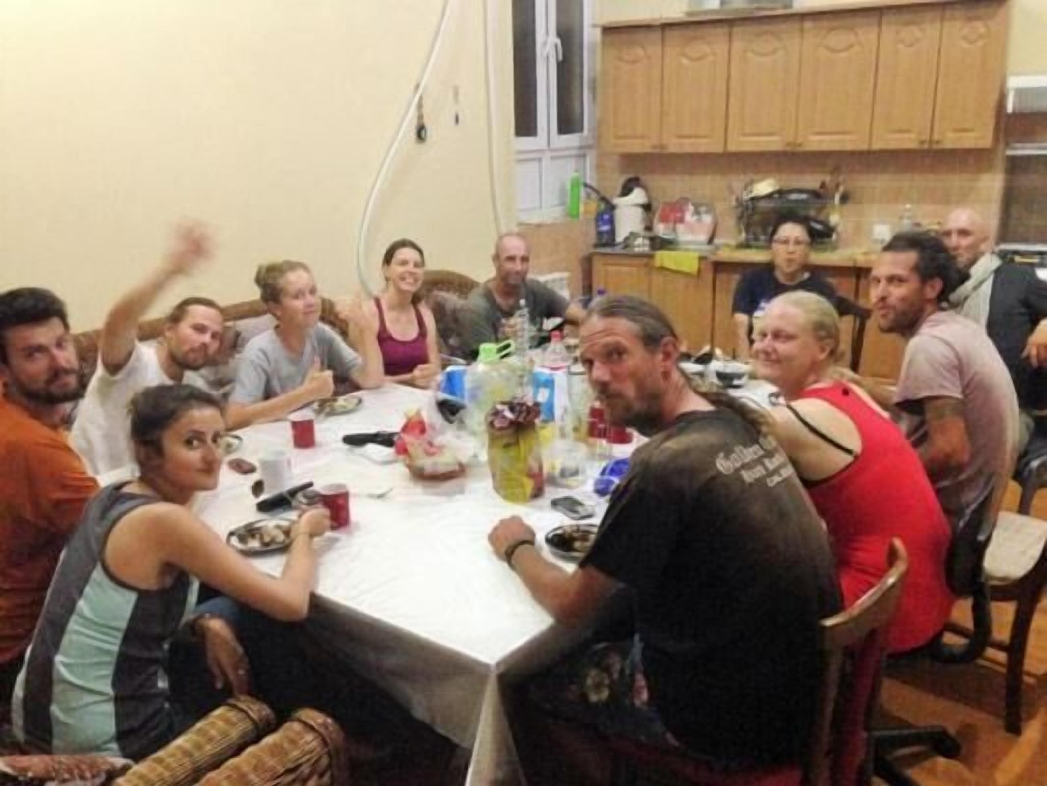 Un grupo de personas sentadas alrededor de una mesa en una habitación con armarios de madera y un ventanal.
