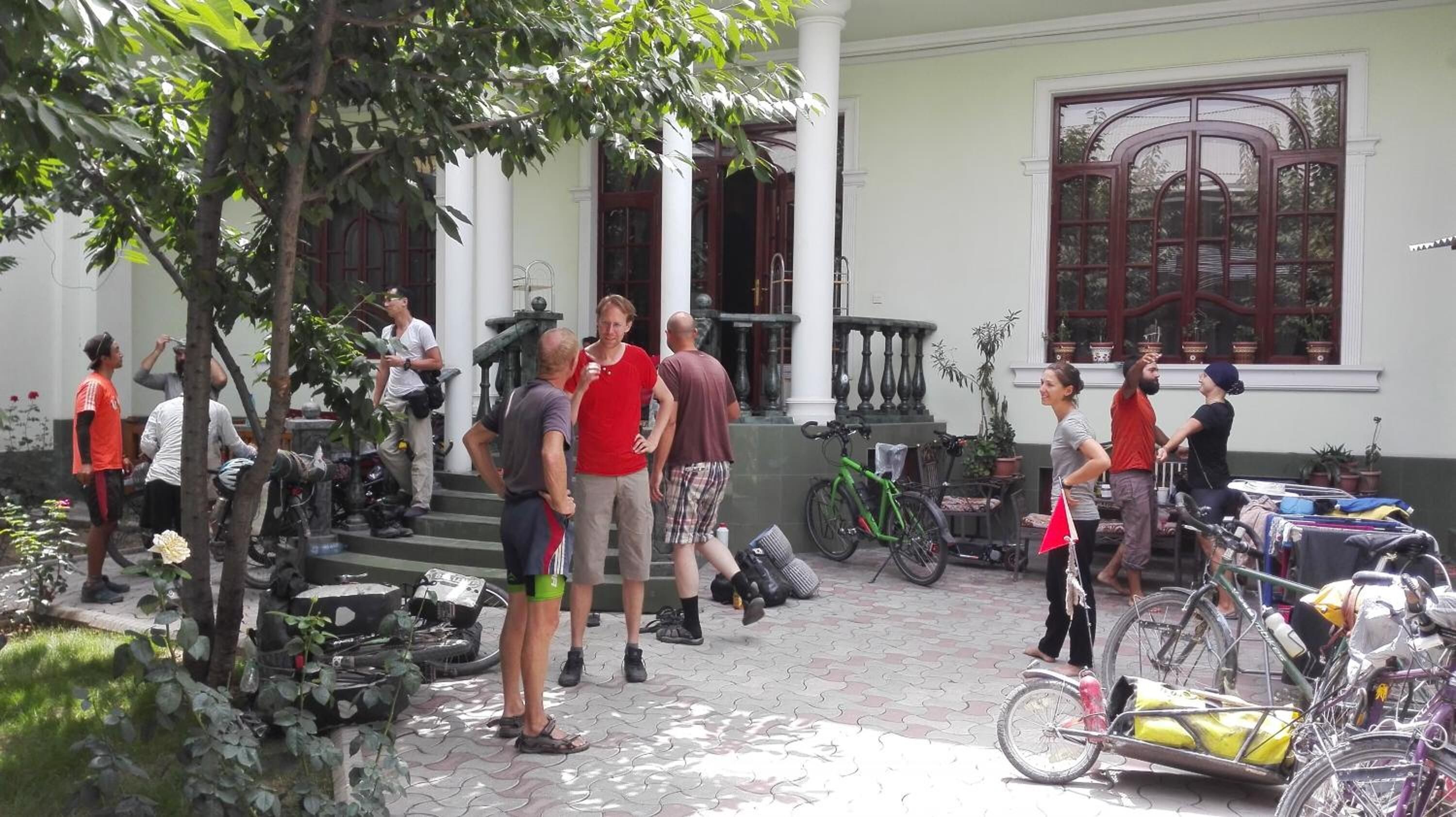 A courtyard with a paved walkway, a green bicycle, and a building with columns and large windows.