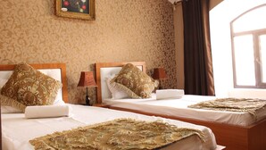 A hotel room with two beds, patterned wallpaper, a framed picture on the wall, and a window with curtains. - Green House Hostel (Dushanbe)
