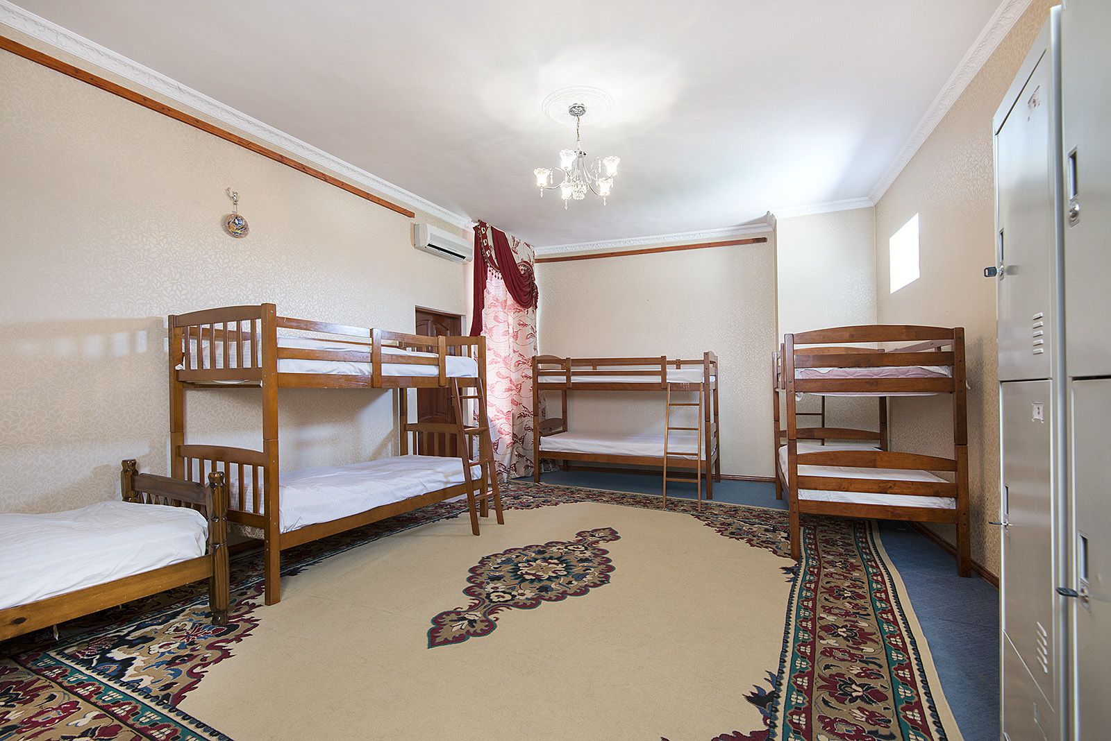 A room with bunk beds, a chandelier, and a patterned carpet.