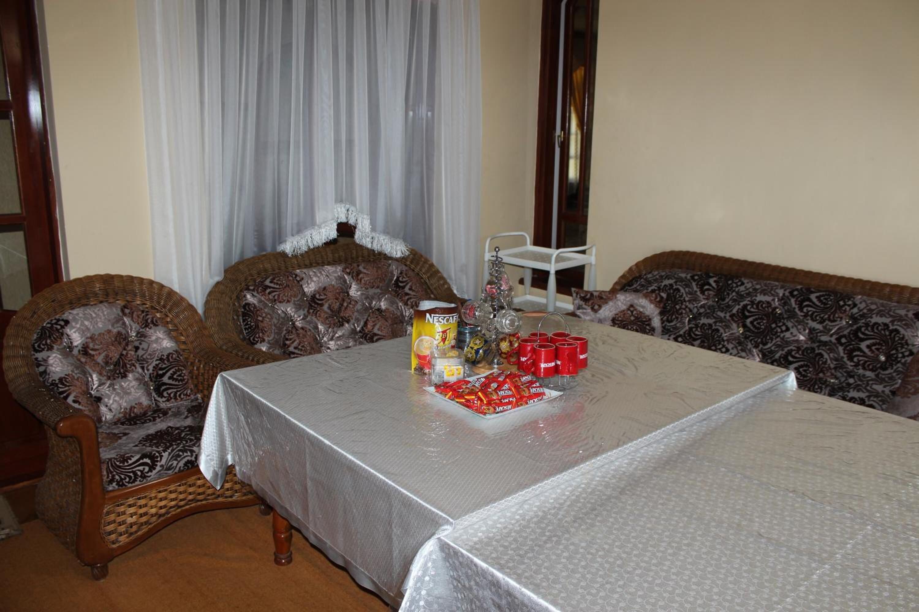 A dining area with a table set for two, featuring a patterned sofa and a chair.