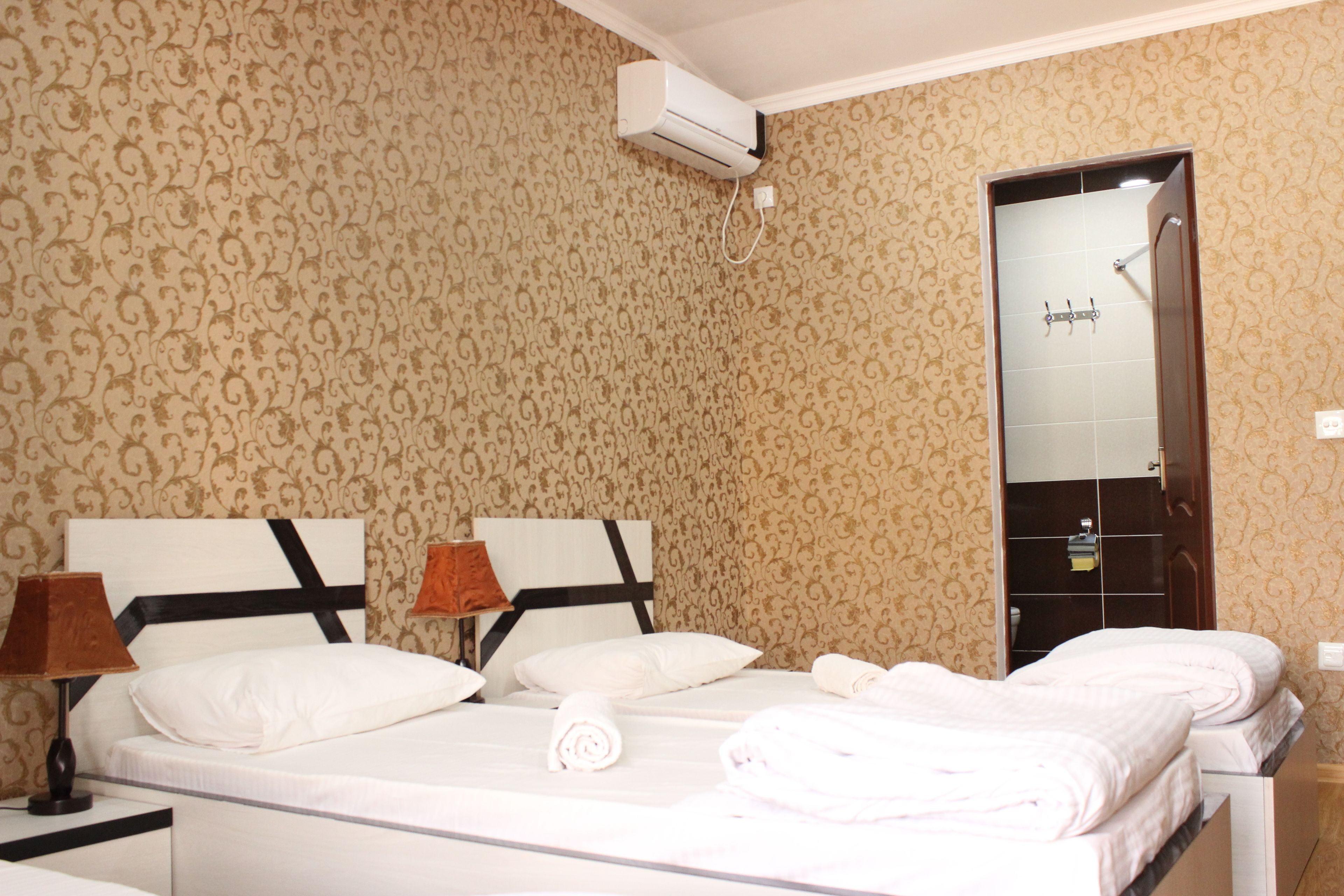 A hotel room with two beds, a large mirror, and a wall-mounted air conditioner.