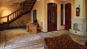 A spacious living room with a wooden staircase, a fireplace, and a dining area. - Green House Hostel (Dushanbe)