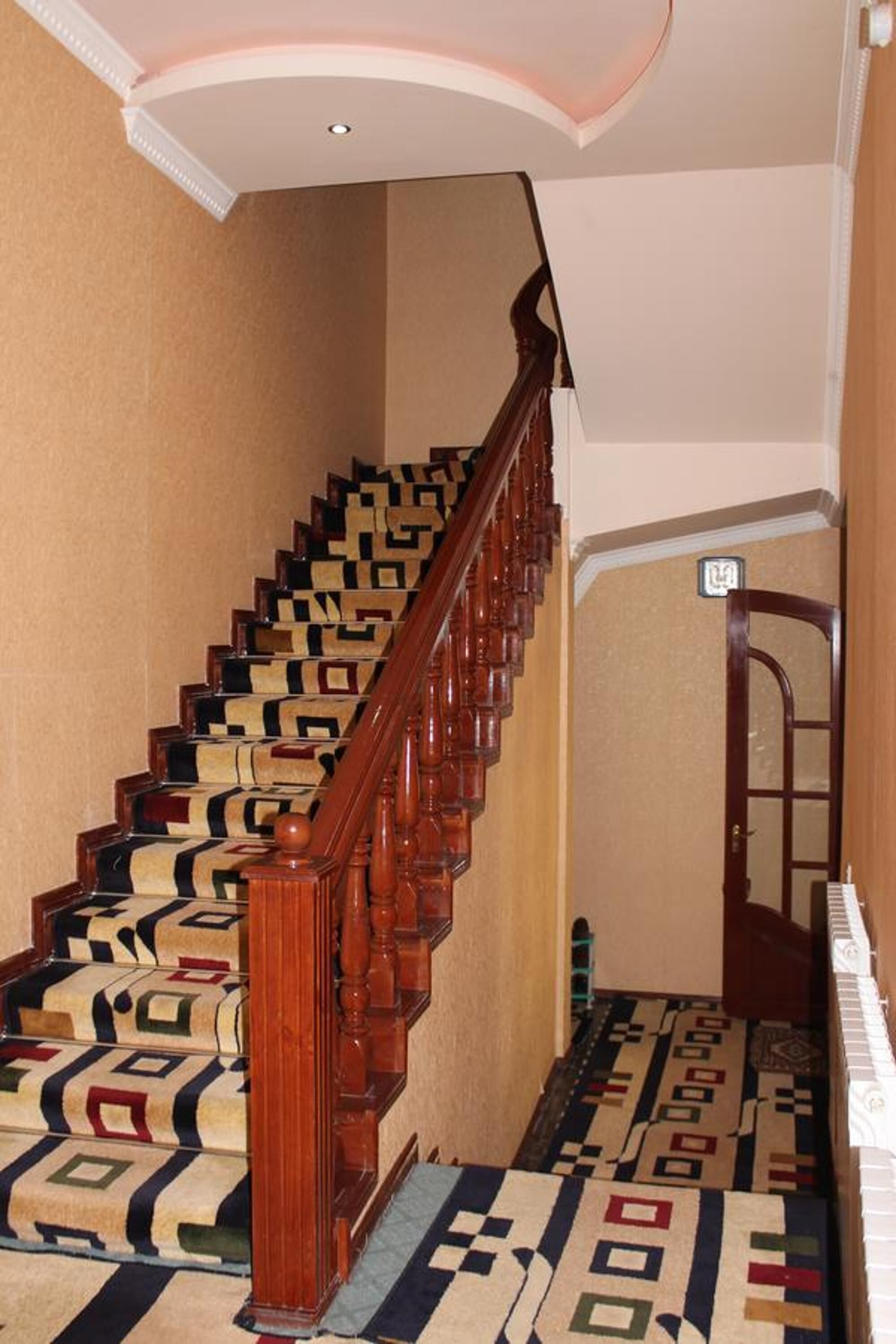 Una escalera con alfombra estampada y barandillas de madera.