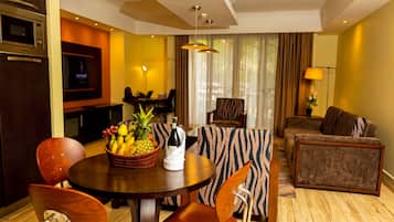 A modern hotel room with a dining area, a sofa, and a television.