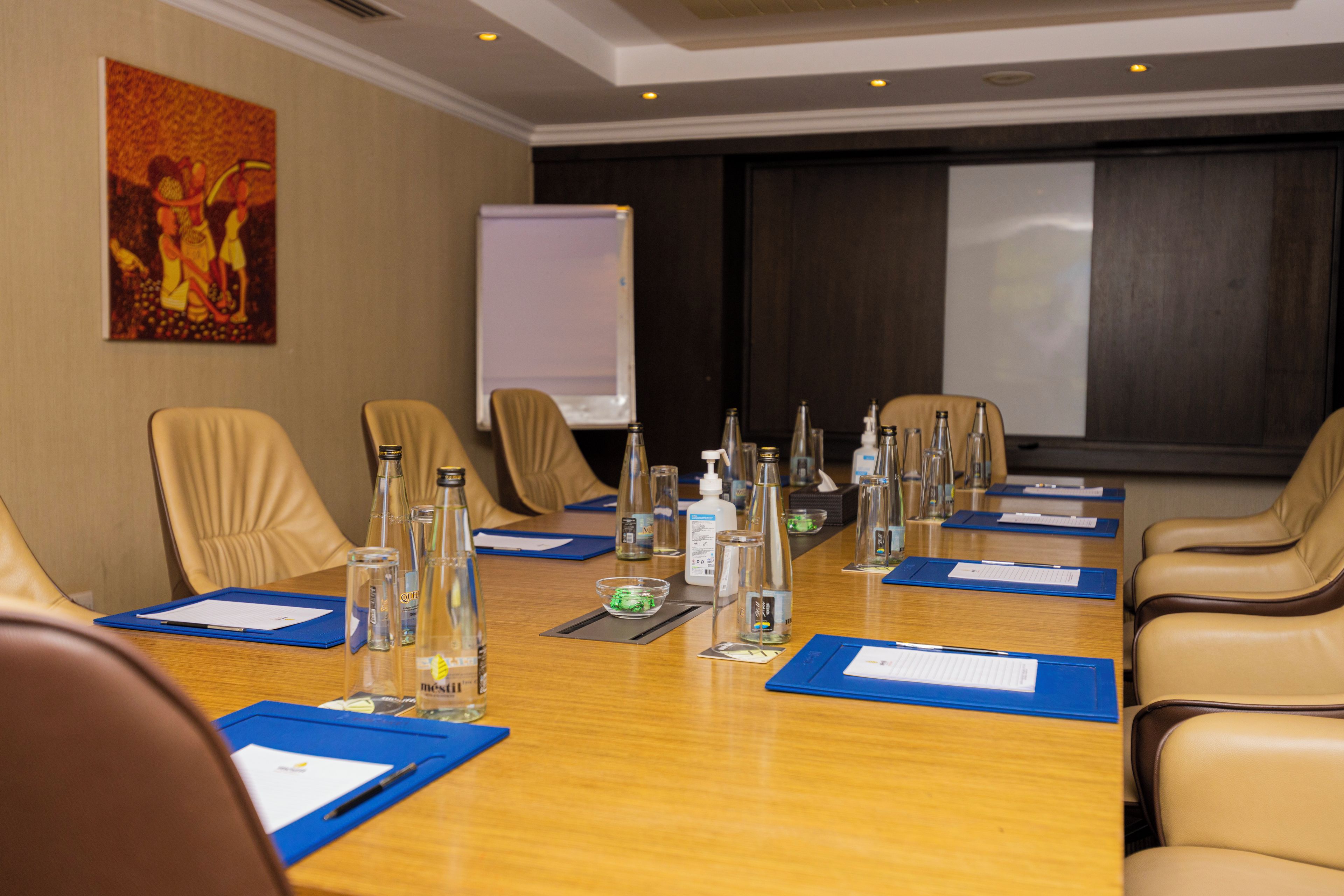 A conference room with a long table, chairs, and various items like bottles and papers.