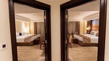 Une chambre d’hôtel dotée d’un grand miroir qui reflète le lit, un bureau et une chaise. La chambre a un plancher en bois et une lampe fixée au mur.