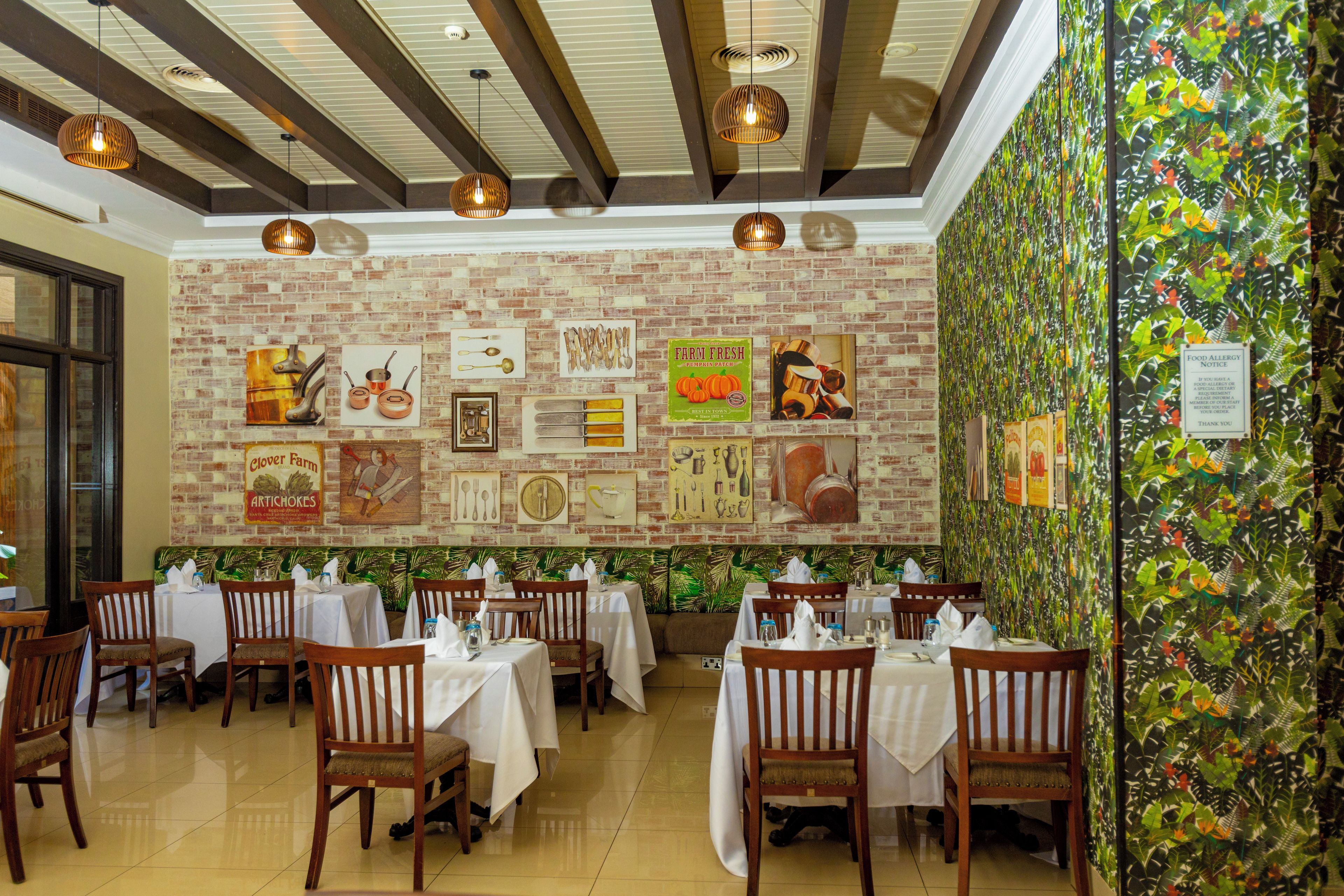 L’intérieur d’un restaurant avec des murs en briques, des suspensions décoratives et des tables dressées pour le service.