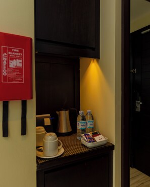 Una kitchenette con un cobertor ignífugo, botellas de agua, una cafetera y un juego de té.