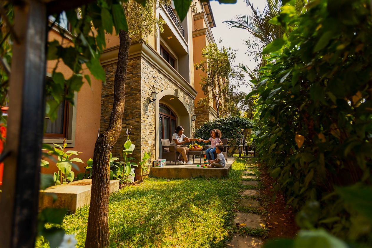 A building with a stone facade, a covered patio, and a lush garden.