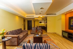 A hotel living room with a sofa set, a coffee table, and a television.