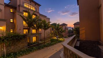 A hotel with multiple floors, a paved walkway, and palm trees.
