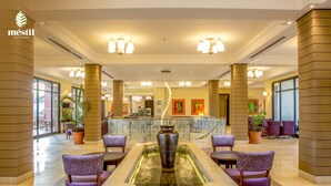 A spacious lobby with a central water feature, seating areas, and a reception desk. - Mestil Hotels & Residences (Kampala)