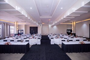 A conference room with multiple round tables, white tablecloths, and black chair sashes. - Mestil Hotels & Residences (Kampala)