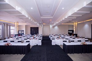 A conference room with multiple round tables, white tablecloths, and black chair sashes.