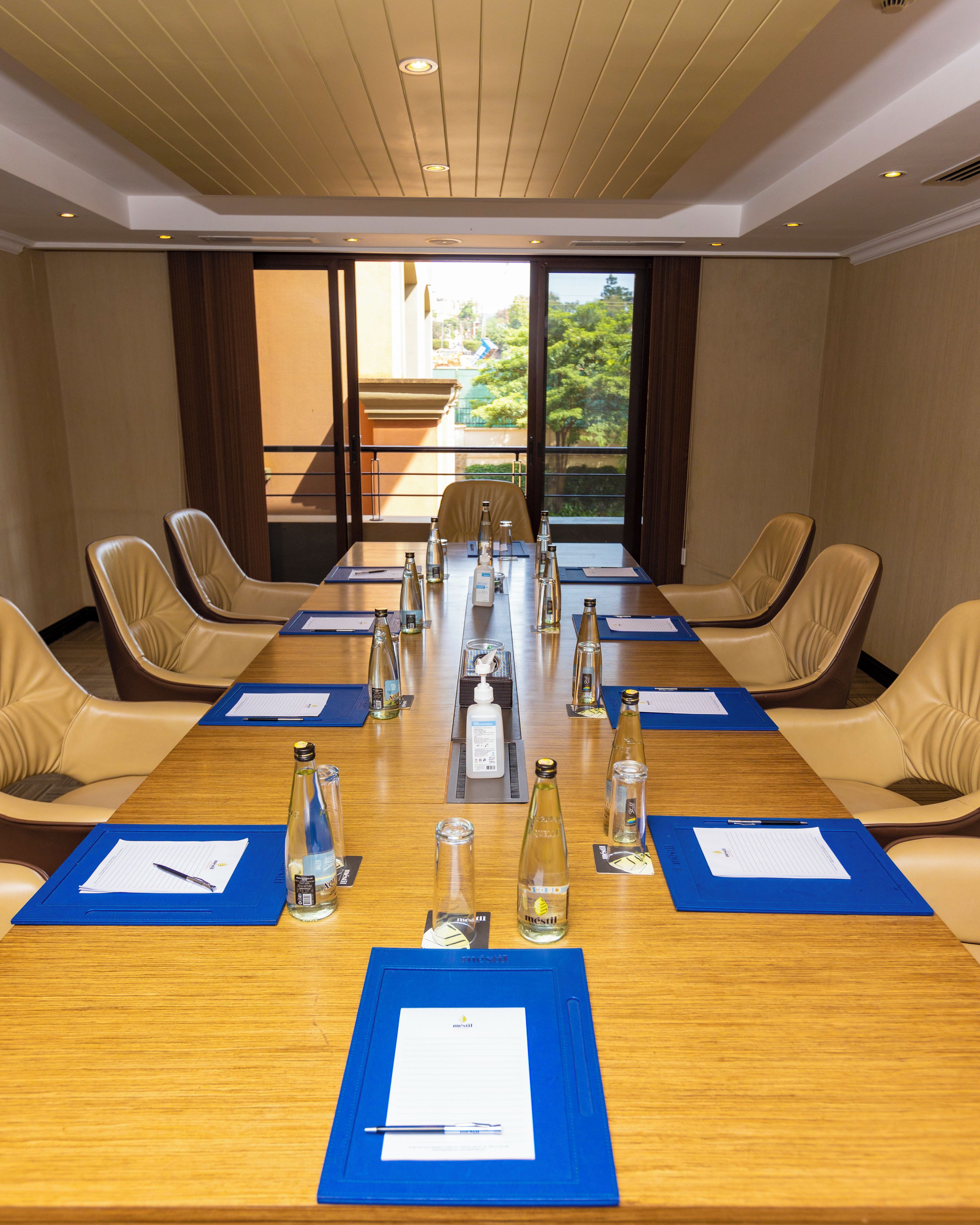 A conference room with a long table, chairs, and various items like bottles and papers.