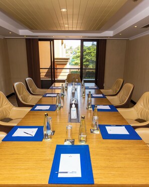 A conference room with a long table, chairs, and various items like bottles and papers. - Mestil Hotels & Residences (Kampala)