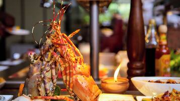 Ein Hummer auf einem Tisch mit verschiedenen Gerichten und einer Kerze.