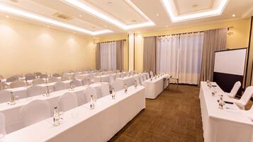 A conference room with long tables, chairs, and a presentation screen.