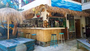 A bar with a thatched roof, bamboo wall, and stools. - Dragon Dive Komodo Dive Resort (Labuan Bajo)