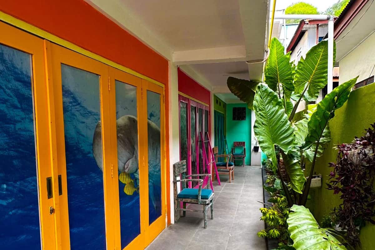 A covered corridor with colorful walls, a tiled floor, and several chairs.