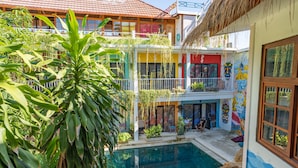 A courtyard with a swimming pool, surrounded by colorful buildings with balconies and plants. - Dragon Dive Komodo Dive Resort (Labuan Bajo)