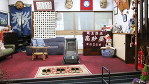 A traditional Japanese room with tatami flooring, a tatami mat table, a heater, and a futon bed. - Takasagoya Ryokan (Yamagata)