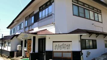 A two-story building with a balcony, a green awning, and a sign with Japanese characters.