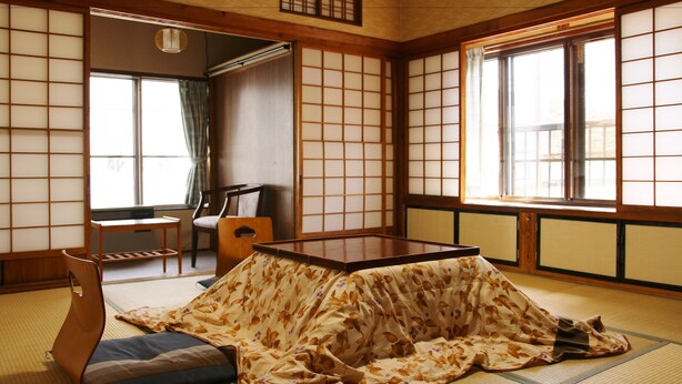 A traditional Japanese tatami room with a low table, cushions, and sliding doors. - Takasagoya Ryokan (Yamagata)