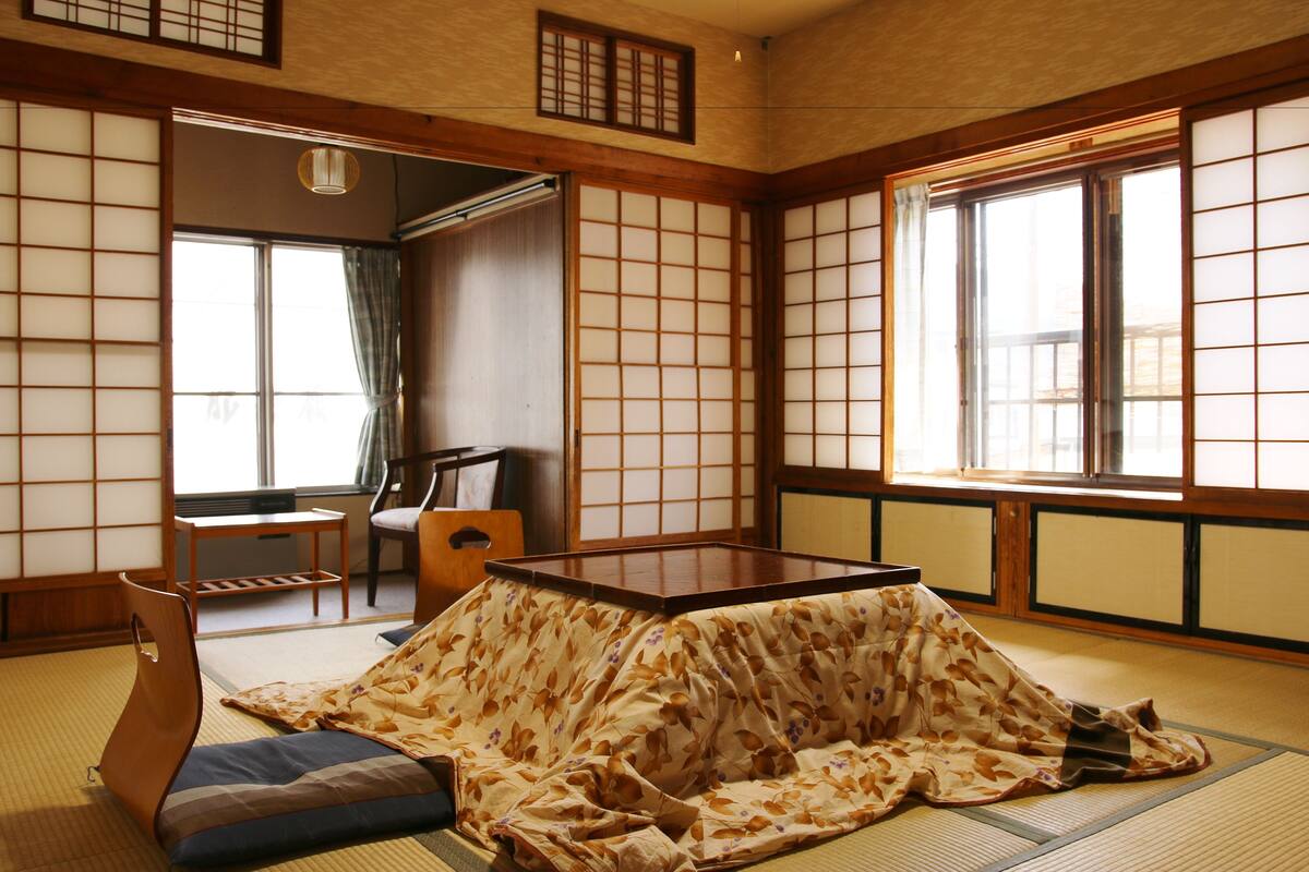 A traditional Japanese tatami room with a low table, cushions, and sliding doors.