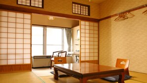 A traditional Japanese room with tatami flooring, a low wooden table, and a sliding door leading to another room. - Takasagoya Ryokan (Yamagata)