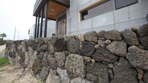 Un edificio moderno con una base de pared de piedra, ventanas amplias y techo de madera.