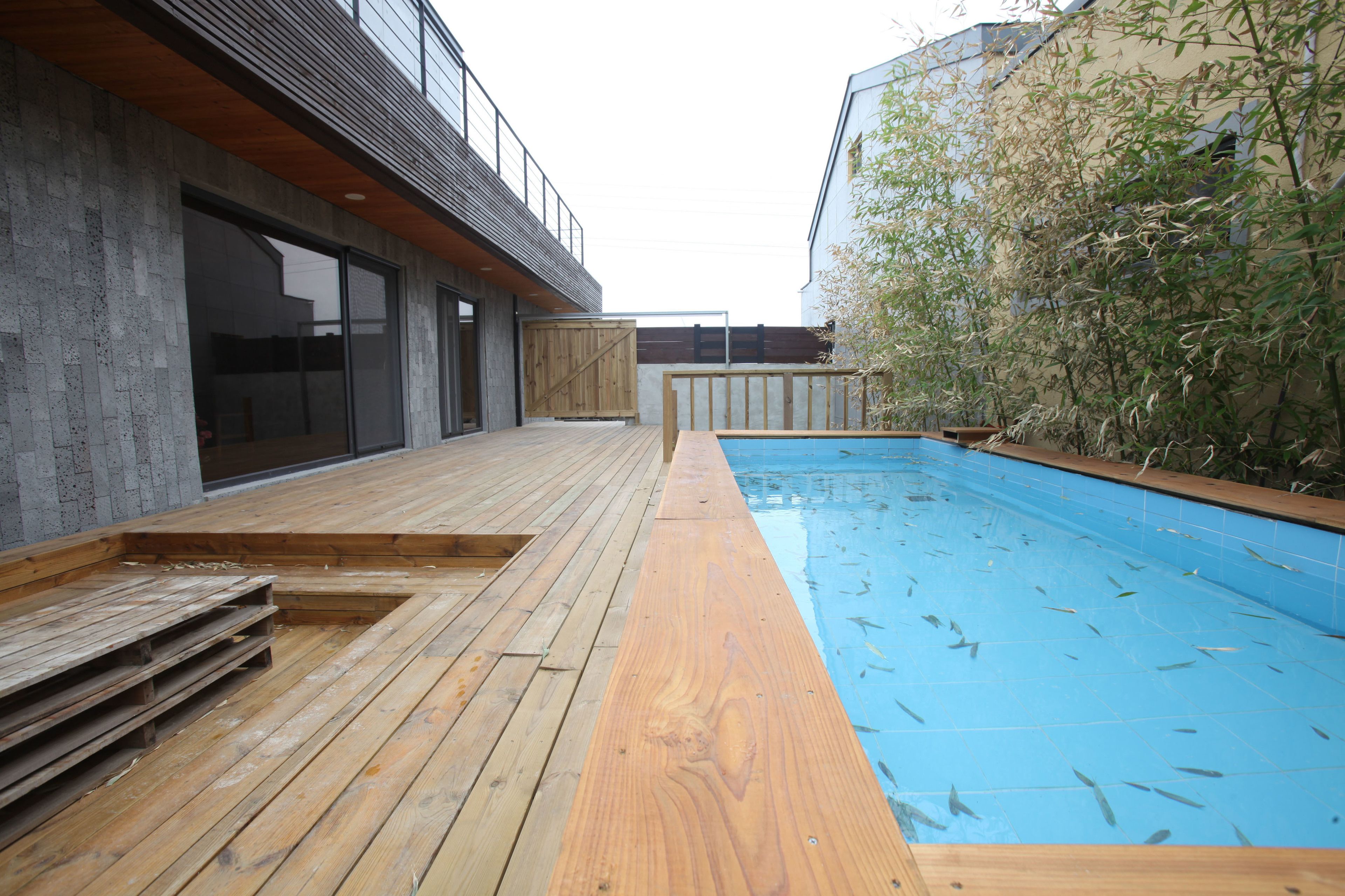 Een modern zwembad met terras en een blauw zwembad.