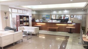 A hotel lobby with seating areas, a reception desk, and a counter. - Itoen Hotel Bekkan (Ito)