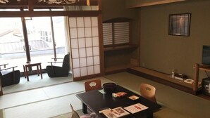 A traditional Japanese-style room with tatami flooring, a low table with cushions, and sliding doors leading to an outdoor area. - Itoen Hotel Bekkan (Ito)