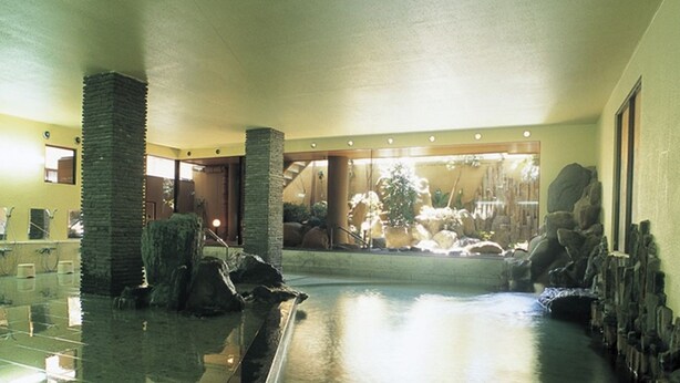 A spacious indoor pool area with a clear view of the outdoors, stone pillars, and a reception desk. - Itoen Hotel Bekkan (Ito)