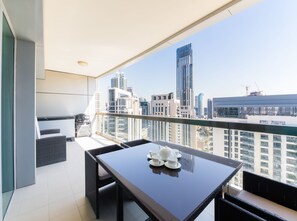 A balcony with a table set for tea, overlooking a cityscape with modern buildings. - Maison Privee - Sterling Tower West (Dubai)