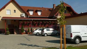 Ein Gebäude mit rotem Dach, ein Auto davor und ein weißer Transporter mit Schrift.