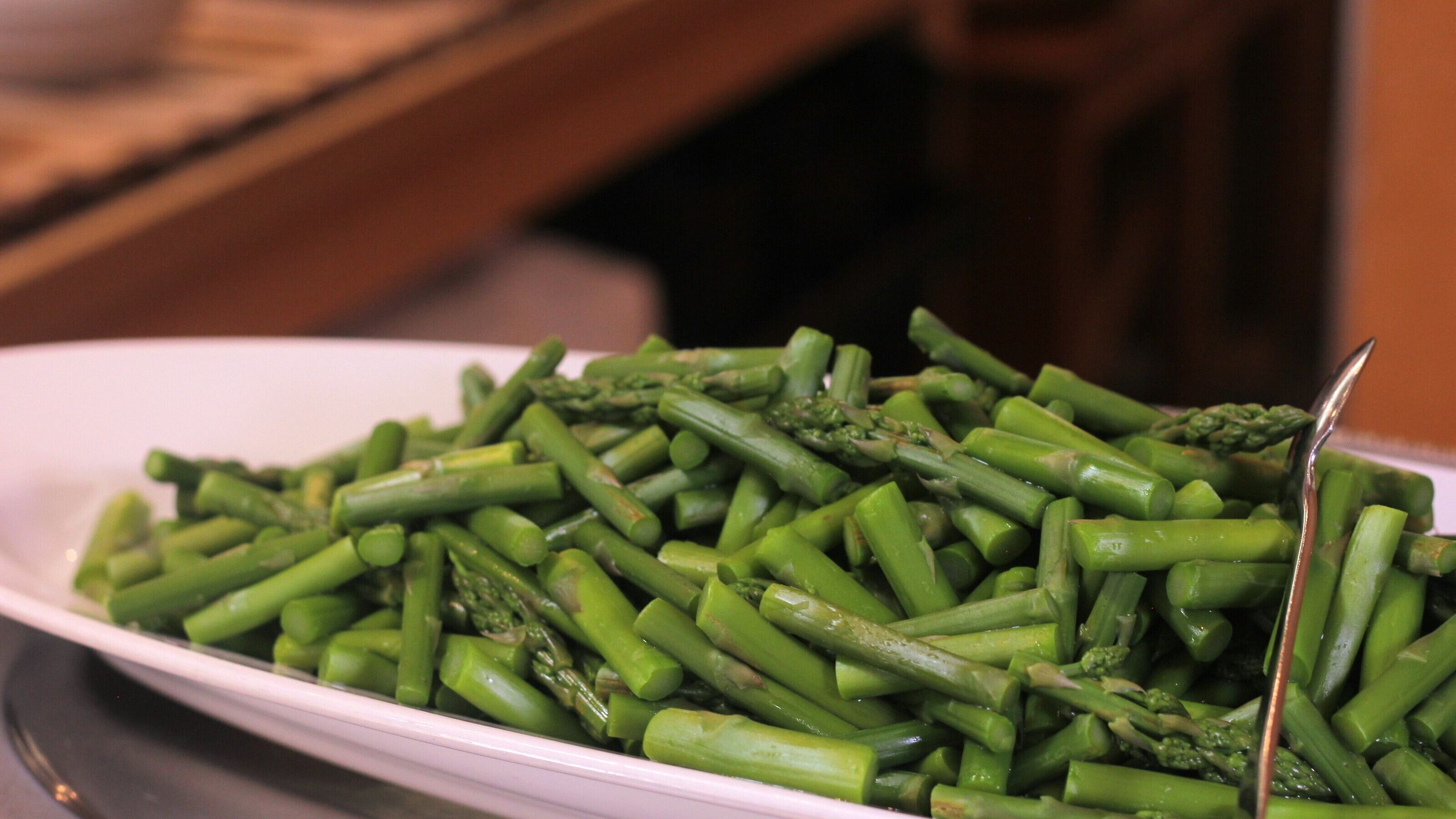 A white plate filled with green asparagus spears.