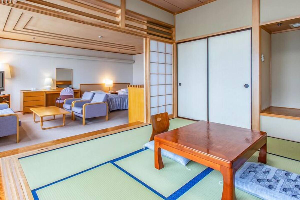A traditional Japanese-style room with tatami flooring, a low wooden table, and a futon bed.