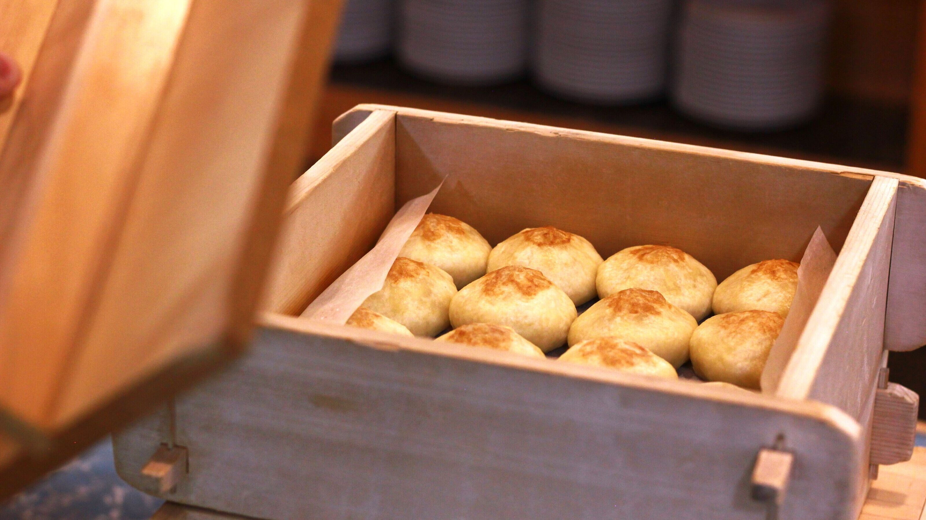 Una caja de madera con varias piezas redondas y doradas, horneadas.