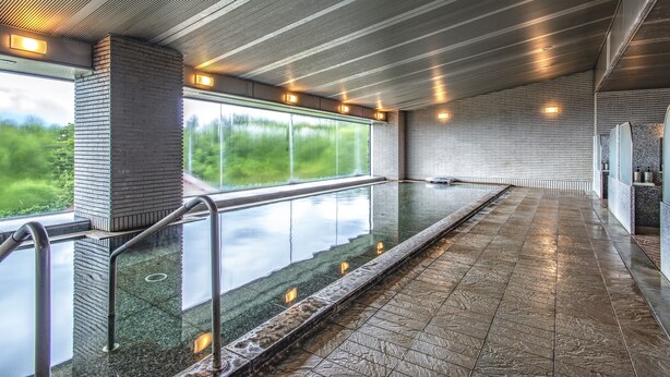 Uma piscina interior moderna com paredes de vidro transparente, grades de metal e chão revestido de azulejos.